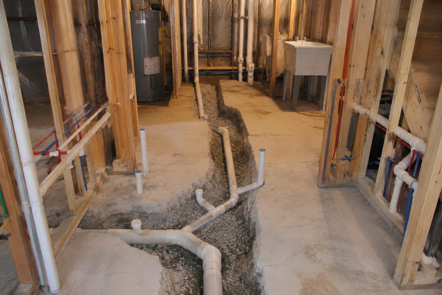 Open trench in a basement floor exposing new underground drain lines