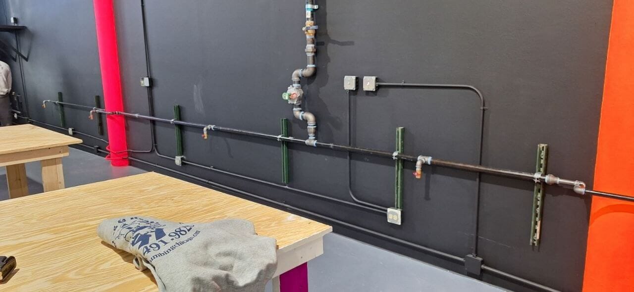 Black iron gas line with shut-off valves run along an interior wall