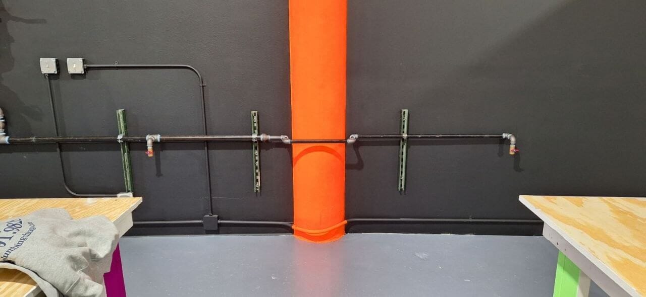 Black iron gas piping installed along a commercial wall
