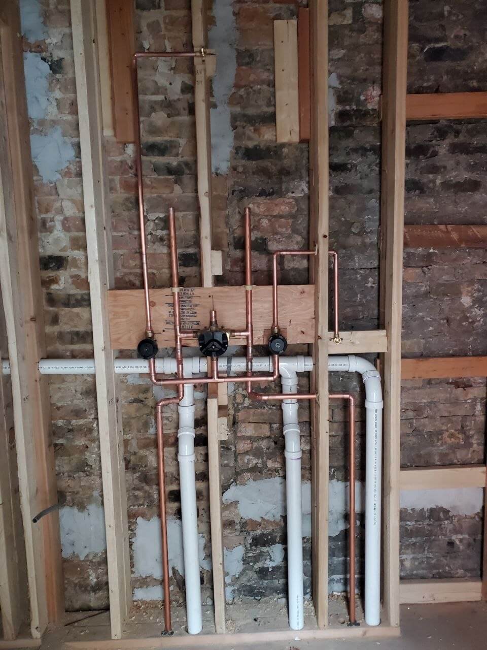 Copper supply lines and shut-off valves in an exposed brick wall