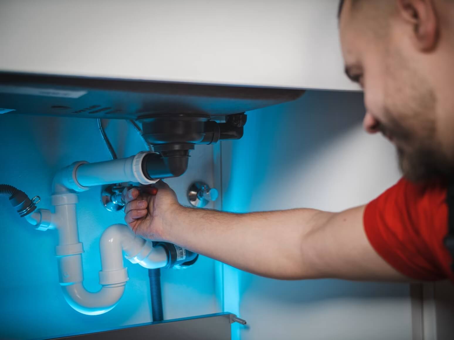 Plumber connecting the drain under a sink