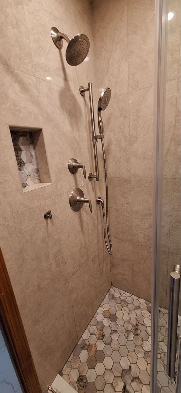 Shower valve with rain shower head and handheld sprayer installed in a tiled shower