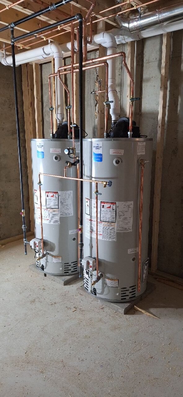 Two Bradford White water heaters with copper piping installed in a basement