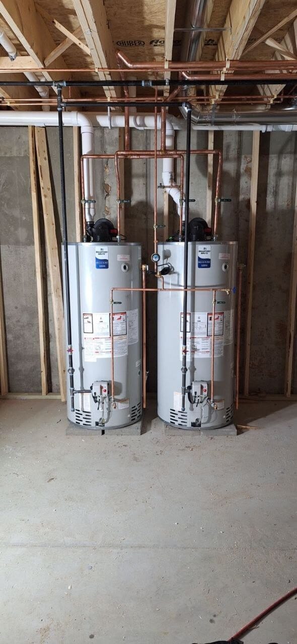 Two water heaters with copper water lines and venting in new construction